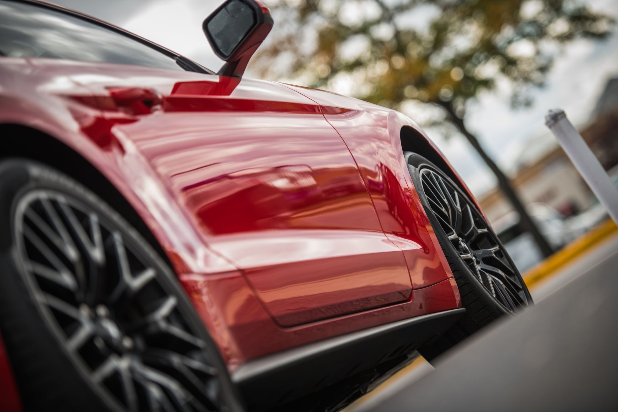 Red Lamborghini speeding down a tree-lined road in Miami, showcasing sleek design and high-performance luxury.